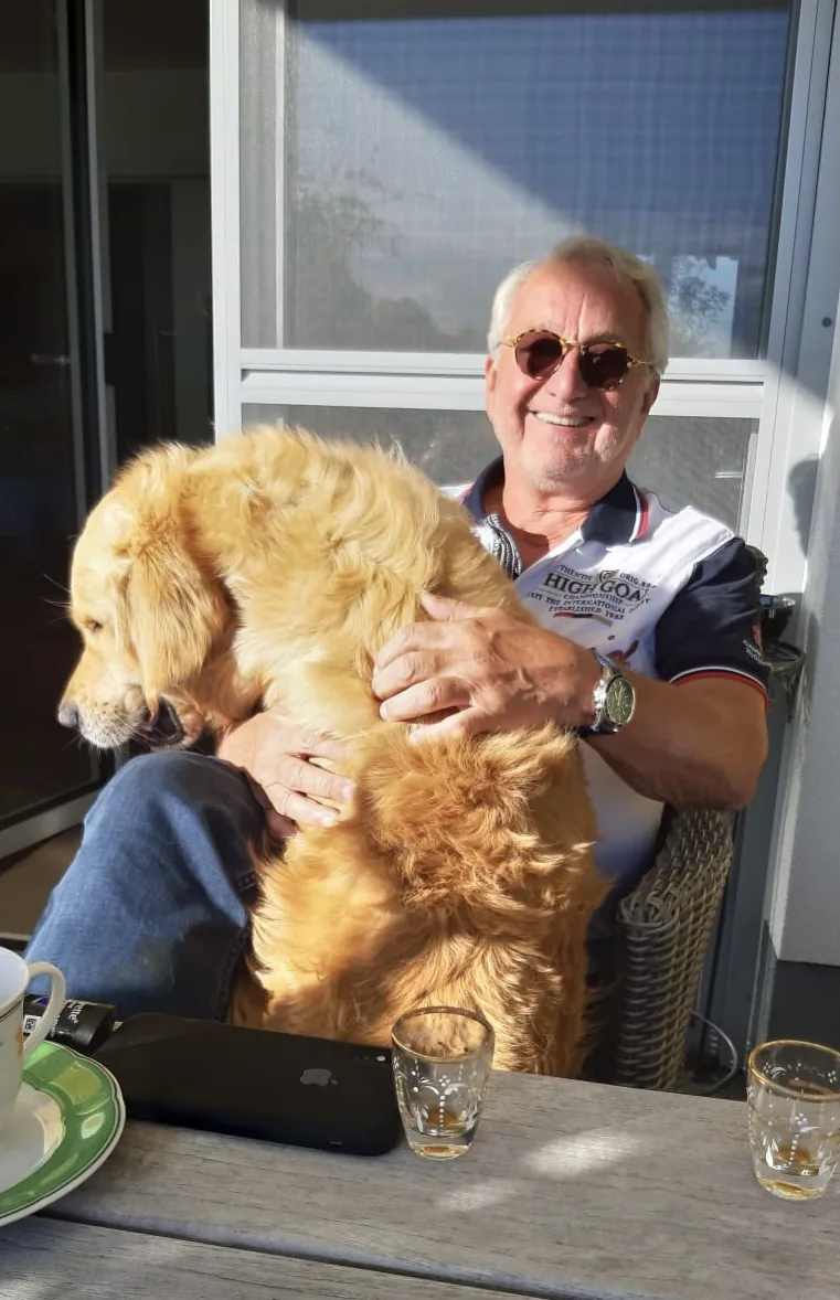 Werner Herzog lachend auf der Terrasse, seinen Golden Retriever im Arm